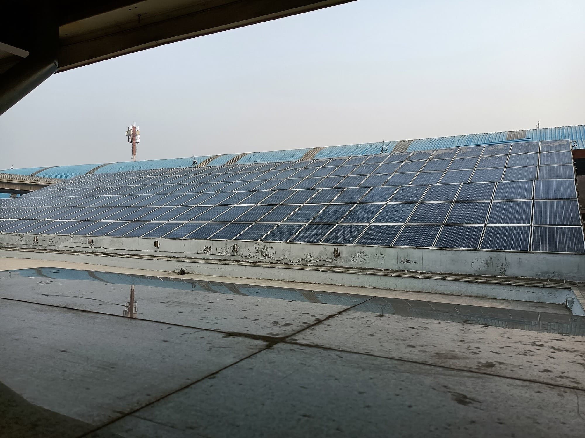 A rooftop array in Delhi after a dry spell, the dust film visible across every module