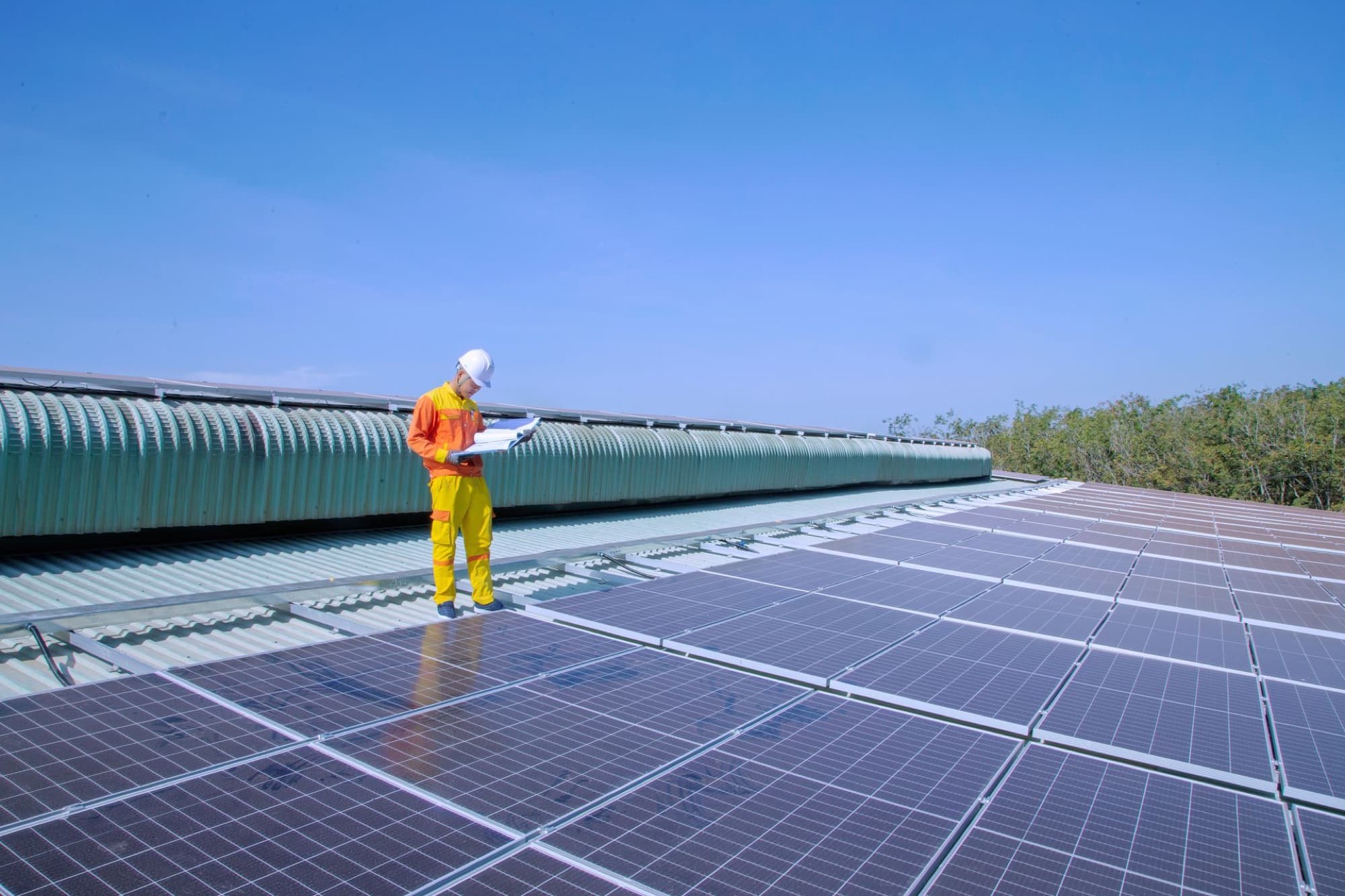 A technician checking an array on a shed roof, checklist in hand